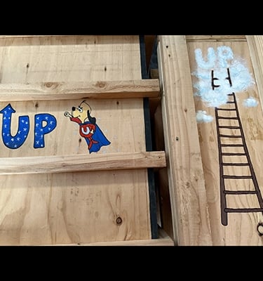 Shipping crates for Talbotics sculpture with image of Underdog and ladder drawn on them.