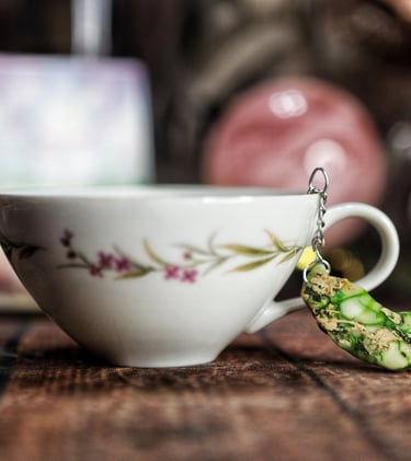 A tea cup with a green stone charm hanging from it