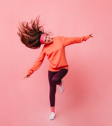 a woman in a pink sweater jumping in the air
