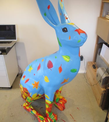 A hare sculpture with autumn leaves and wildlife painted by Laura Fearn