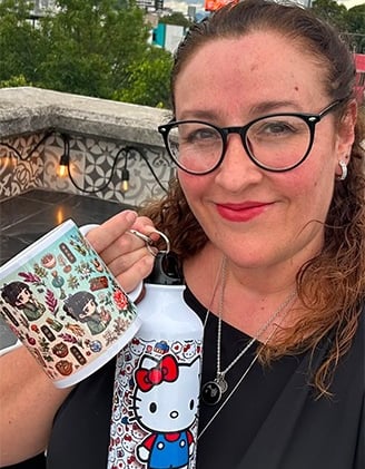 Una mujer sonriente sostiene una botella de agua de Hello Kitty y una taza de café estampada en una