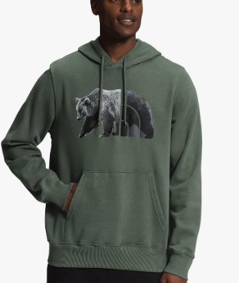 a man in a green hoodie with a bear in the background