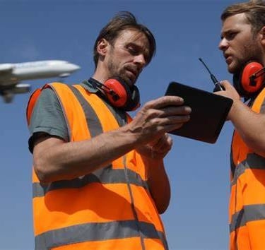 Airport workers reviewing data and talking on their PoC radios.