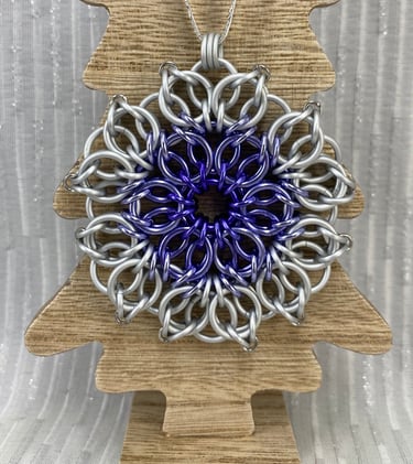 An ornament crafted from chainmaille. Purple and white.