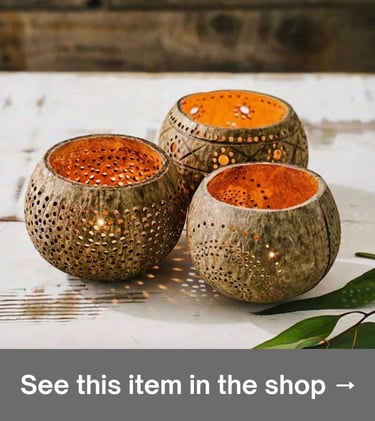 Set of three carved coconut shell candle holders with warm light, adding a boho touch to home decor.