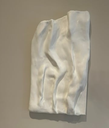 White textured wall sculpture with subtle raised forms catching natural light and shadow.