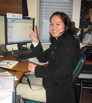 a japanese woman sitting at a desk with a computer and a laptop