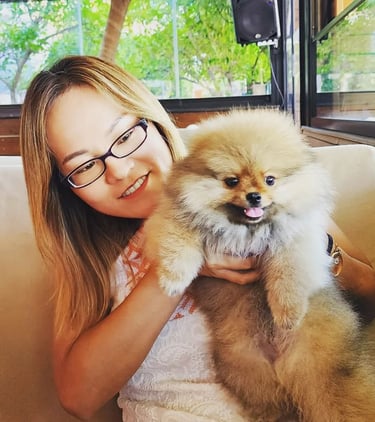 a japanese woman in glasses and a white shirt is holding a dog
