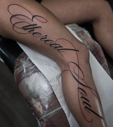 Cursive script tattoo on a leg featuring the words Ethereal Soul in elegant black ink.