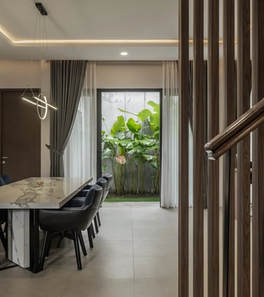 Interior ruang makan yang elegan dengan meja makan dari marmer, kursi beludru biru tua, dan lampu ga