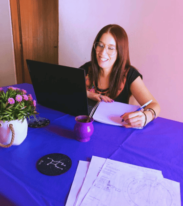 a woman sitting at a table with a laptop and a notebook