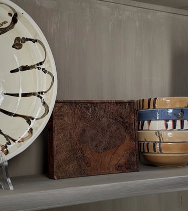 Two lit tea light candles resting in smooth, pebble-shaped wooden holders on a dark surface.