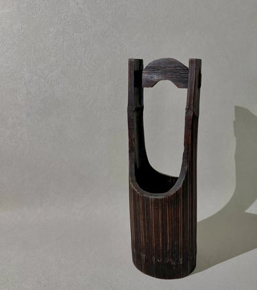 Handcrafted dark brown bamboo flower vase with a traditional Japanese hanging handle design.