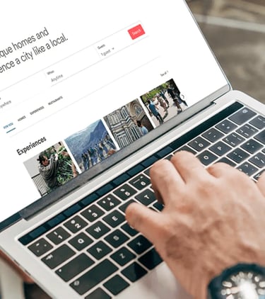 A person using a laptop to browse the Airbnb website for vacation rentals and travel experiences.