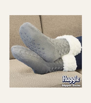 picture of feet wearing grey Ontel Huggle Slipper socks with grip on a couch