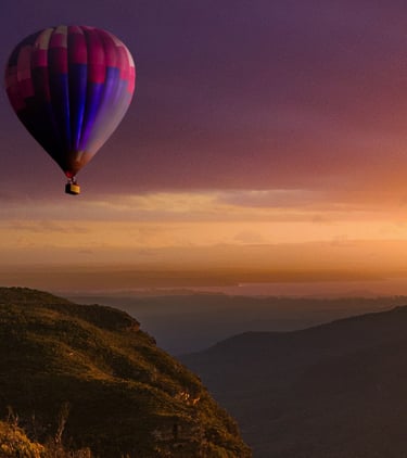 hot air balloon flying over a canyon at sunrise
