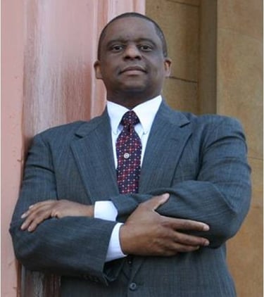 Mark T Stewart in a suit and tie is standing in front of Old Courthouse