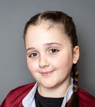 a girl with a ponytail in a rugby tshirt  is smiling towards the camera