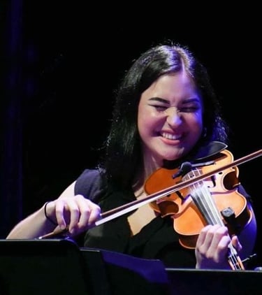 Musician Evelyn Thom smiling with her eyes closed while playing the fiddle.