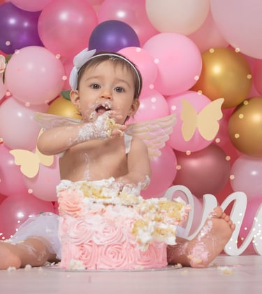 a baby girl sitting in front of a cake