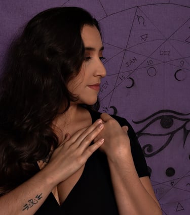 mulher cabelo preto com as mãos no ombro de blusa preta olha para olho de hórus e mapa astral