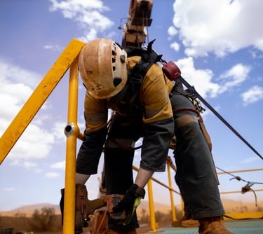 mine site worker in a harness with attached laynard working at heights
