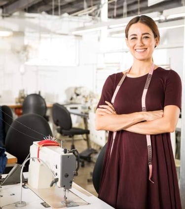 una chica esta en un taller de costura con una cinta medidora colgando del cuello