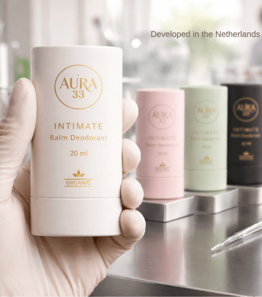 Hand in a glove holding Aura 33 Organic Intimate Balm Deodorant in a laboratory setting.