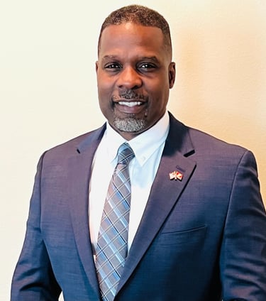 Dr. Marlon Ware professional headshot in blue suit with blue striped tie