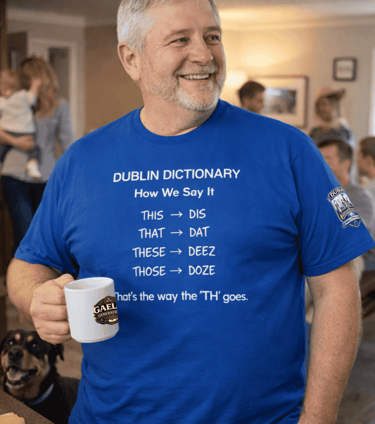 A smiling man wearing a blue Dublin Dictionary t-shirt while holding a white coffee mug.