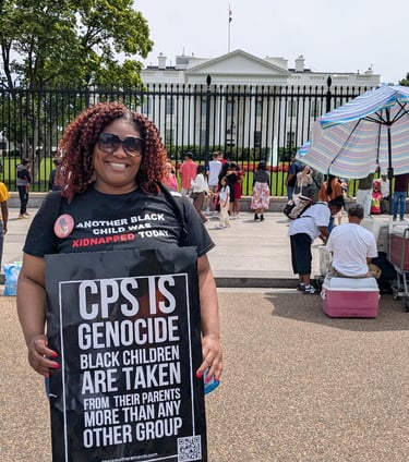 Lucky in front of White House wearing Black Mothers March shirt & holding a "CPS is Genocide" sign. 
