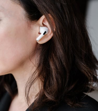 Profile of a women with long, dark hair, with air pods in her ears.