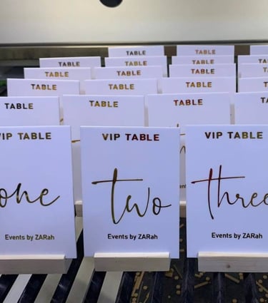 Assorted white Acrylic Table Numbers with black and gold script, labeled from 'one' to 'four'