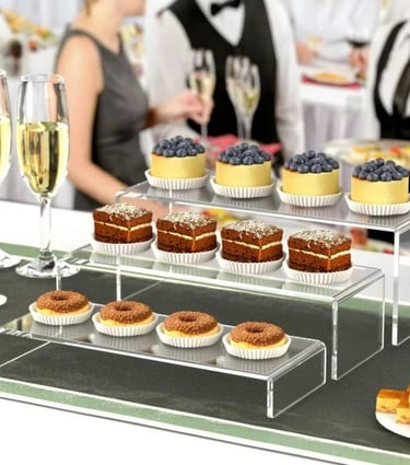 Acrylic risers with a selection of desserts, adding elegance to a catered event setup.