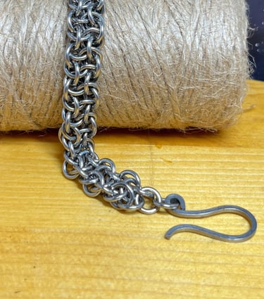 Photo of a chainmaille bracelet made of stainless steel draped over a bundle of jute twine