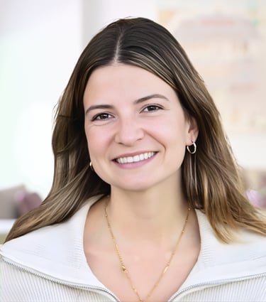 Professional headshot of a smiling woman with brown hair wearing a white sweater and gold jewelry.