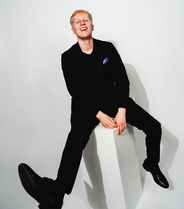 Promovalokuva Taikurista, joka istuu ja hymyilee