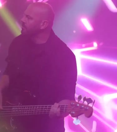 a man with a guitar and a guitar in front of a purple light