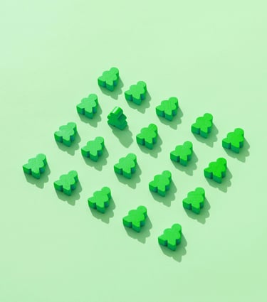 Groene houten poppetjes, allemaal liggend behalve één die rechtop staat, symbool voor regels en mens