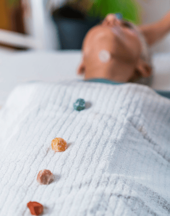 Une personne allongée, recevant un soin de lithothérapie, entourée de cristaux et pierres précieuses