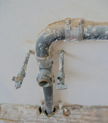 Préparation des arrivées d’eau et évacuation en attente pour lavabo, avec tuyaux et vannes apparente