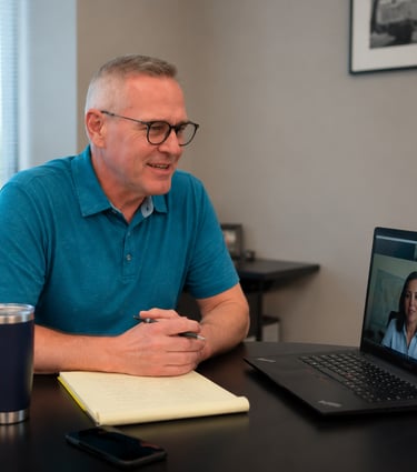 Doug having a professional video conference call on his laptop in a modern office.