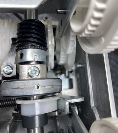 Close-up of the gears and other moving metal and plastic parts inside a sewing machine. 