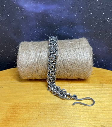 Photo of a chainmaille bracelet made of stainless steel draped over a bundle of jute twine