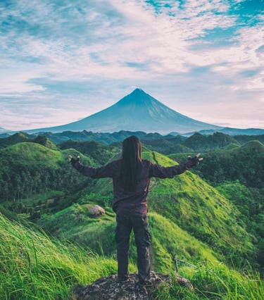 une personne debout sur une colline avec une montagne en arrière-plan