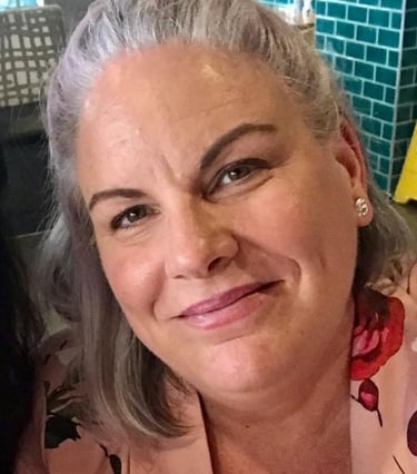 a woman with grey hair and a pink shirt
