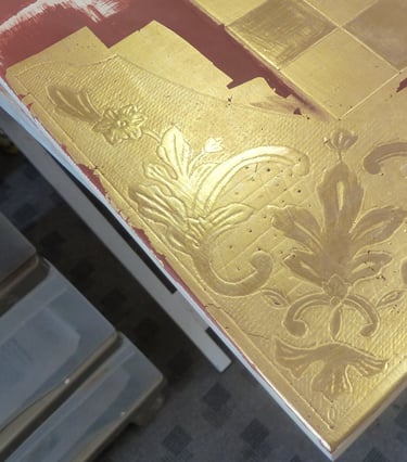 Détail de la pose de dorure à la feuille d'or pour le décor d'un échiquier.
