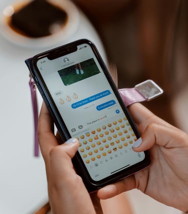 Una persona que utiliza un iPhone para enviar mensajes de texto y emojis mientras está sentada en un