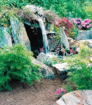 Slate stone grotto with hidden hot tub behind waterfall flowing into natural pool. Carmel Valley, CA