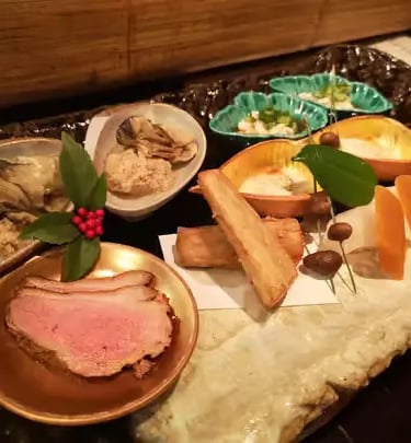 Elegant kaiseki appetizer spread with multiple small dishes on a stone plate, Kyoto cuisine
